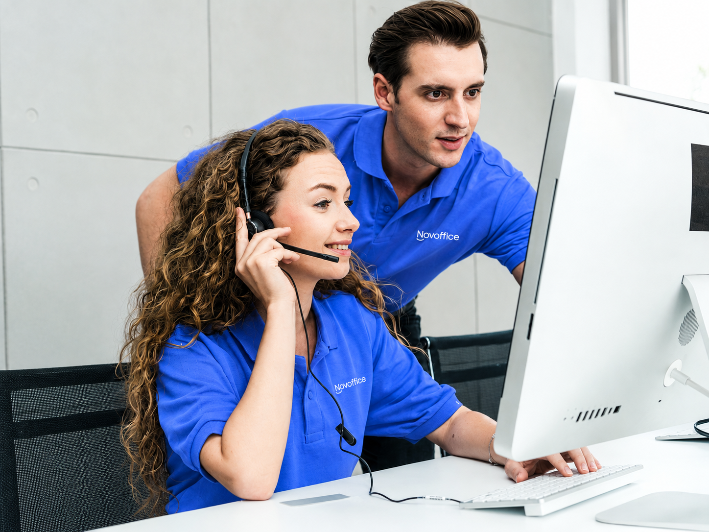 Offers Header — two blue-clad Novoffice team members assisting a remote client via computer, one wearing a headset.