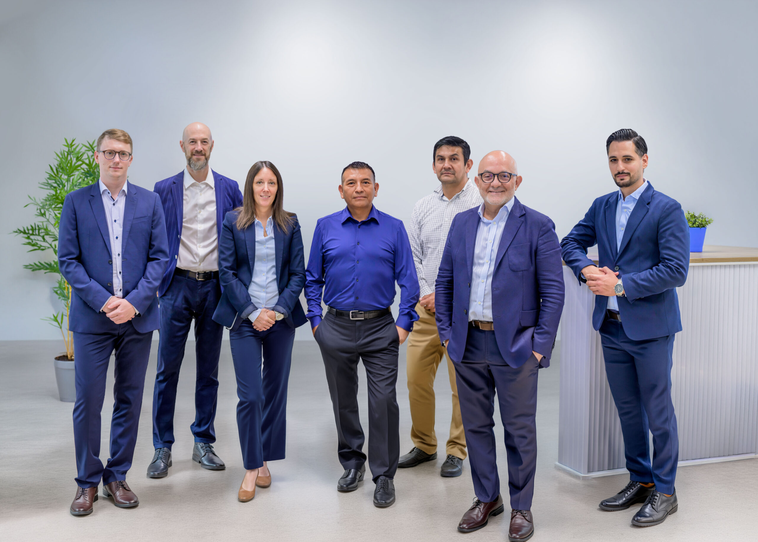 Novoffice team, seven office professionals posing together in a modern space with green plants.